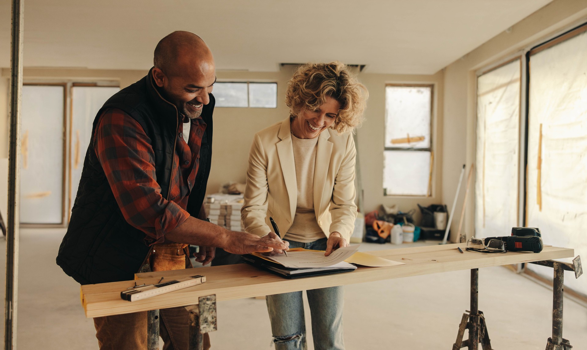 Happy construction worker and homeowner signing renovation contract